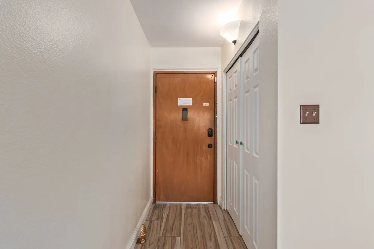 A vantage point of the entryway with the front door and closet doors visible, complemented by a modern light fixture. The neutral decor suggests a smooth transition from the outside world into a well-maintained, welcoming home environment.