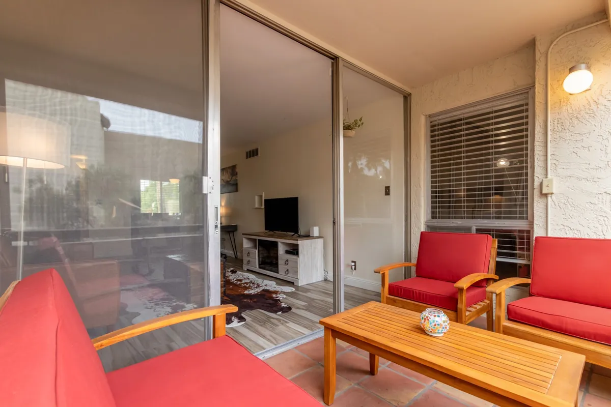 A comfortable living space with red chairs, a wooden coffee table, a TV, and curated interior decor. Morning light streams in, creating a warm and inviting atmosphere ideal for socializing or cozy movie nights.